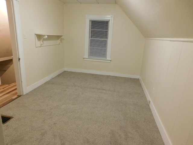 additional living space featuring visible vents, a heating unit, carpet flooring, and vaulted ceiling