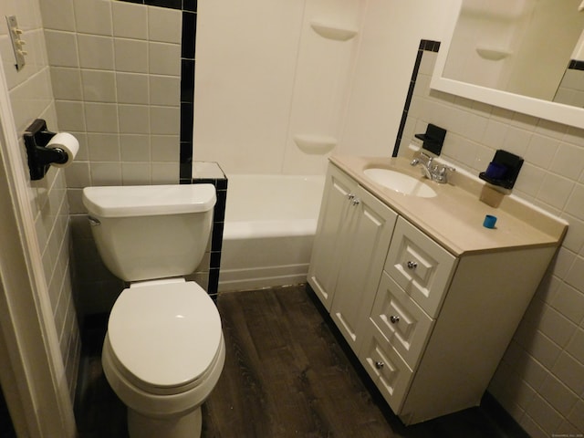 bathroom with toilet, tile walls, vanity, and wood finished floors