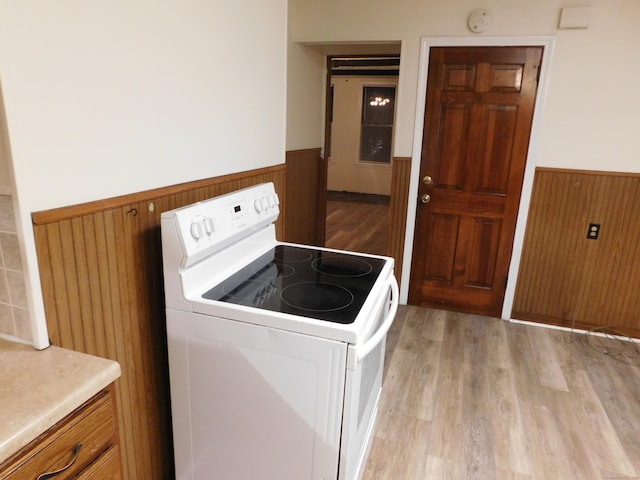 laundry area with a wainscoted wall, wooden walls, light wood-style flooring, and laundry area