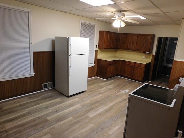 kitchen with white appliances, a wainscoted wall, visible vents, a paneled ceiling, and wood walls