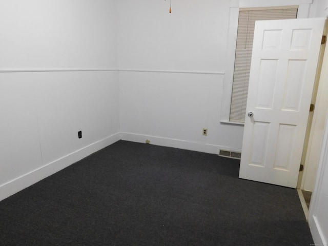 spare room with visible vents, baseboards, and dark carpet