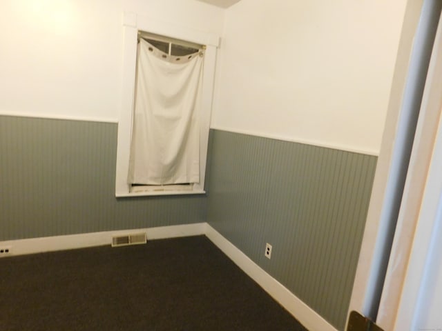 empty room featuring visible vents and a wainscoted wall