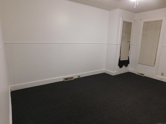 unfurnished room featuring visible vents and dark carpet