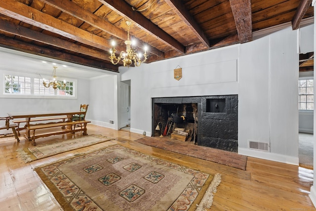 living area featuring visible vents, wooden ceiling, a notable chandelier, a fireplace, and beam ceiling