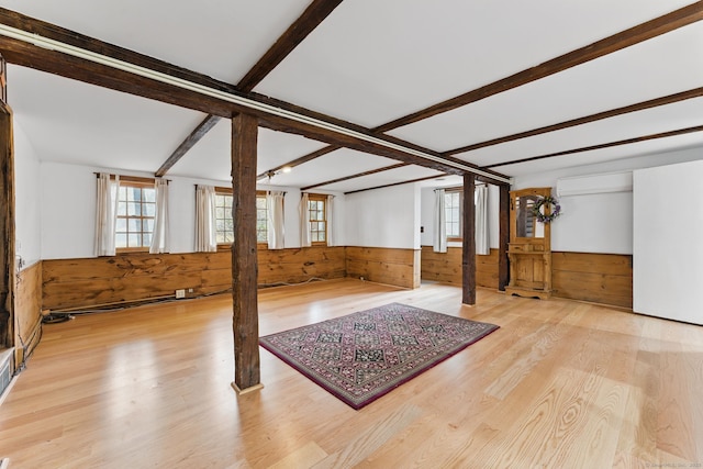 interior space with a wainscoted wall, plenty of natural light, wooden walls, and wood finished floors