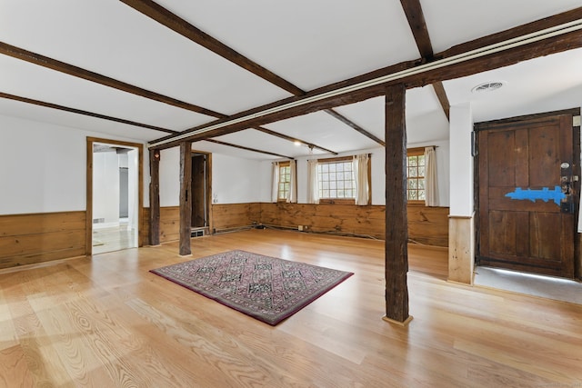 interior space featuring visible vents, wainscoting, wooden walls, wood finished floors, and beamed ceiling