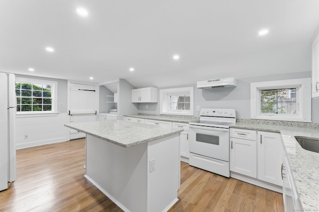 kitchen with white appliances, white cabinets, light wood-style flooring, a center island, and under cabinet range hood