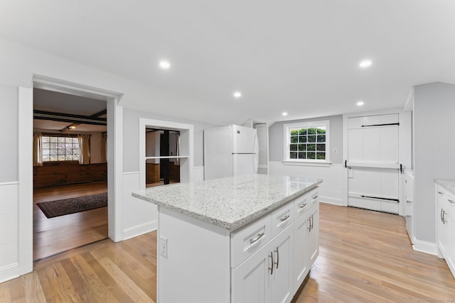 kitchen featuring light wood finished floors, a center island, baseboard heating, and freestanding refrigerator