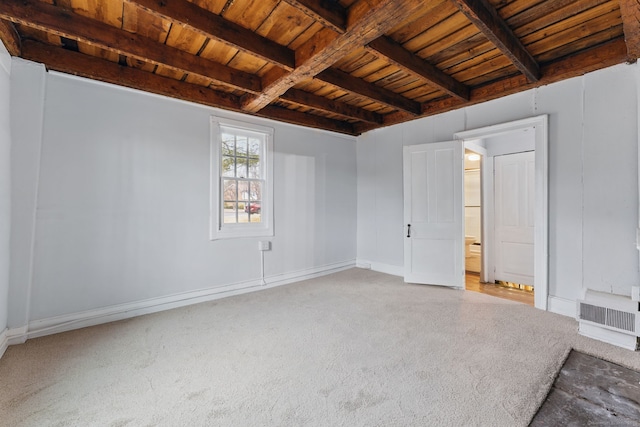 spare room featuring light carpet, baseboards, visible vents, wood ceiling, and beamed ceiling