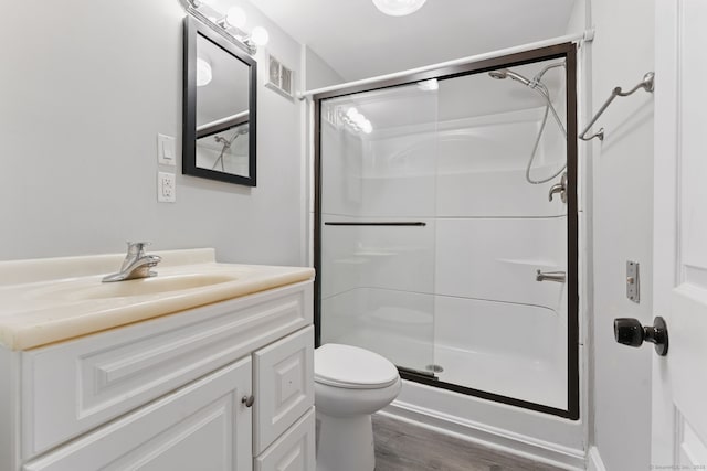 full bath featuring wood finished floors, a stall shower, vanity, and toilet