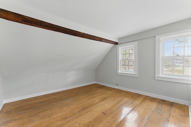 additional living space featuring vaulted ceiling with beams, baseboards, and light wood-style floors