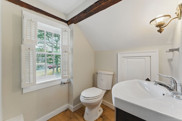 half bath with vaulted ceiling with beams, toilet, a sink, wood finished floors, and baseboards