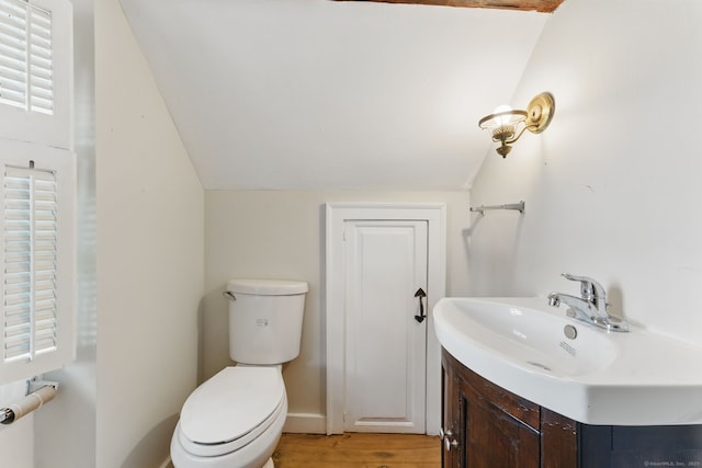 half bath with vaulted ceiling, vanity, toilet, and wood finished floors