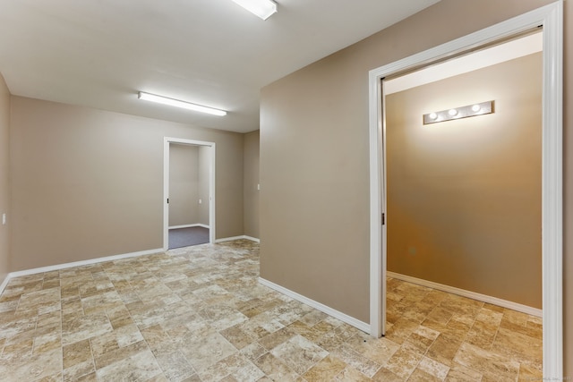 empty room featuring stone finish floor and baseboards