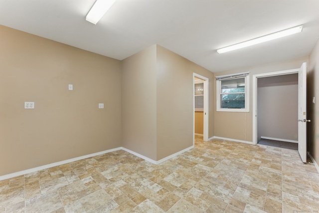 unfurnished room with stone finish floor and baseboards