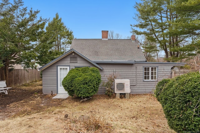 rear view of property with ac unit, fence, and roof with shingles