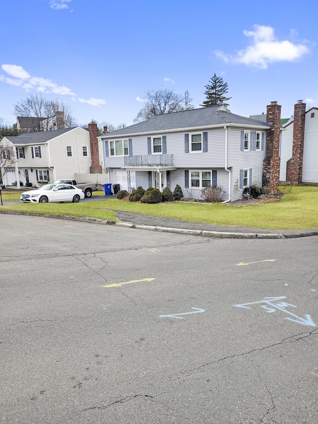 colonial-style house with a residential view, driveway, and a front lawn