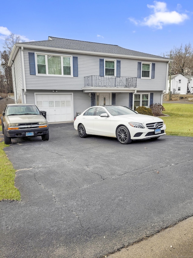 view of front facade with aphalt driveway, a balcony, and an attached garage