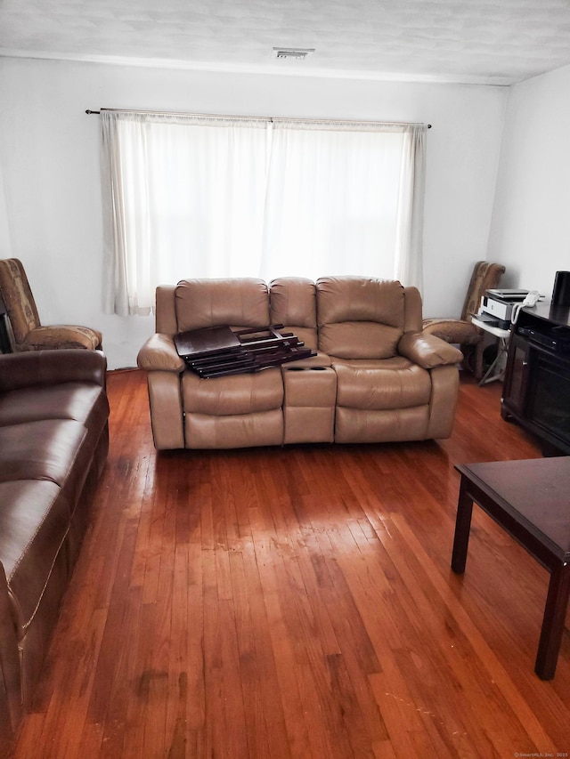 living room with hardwood / wood-style floors, visible vents, and a healthy amount of sunlight