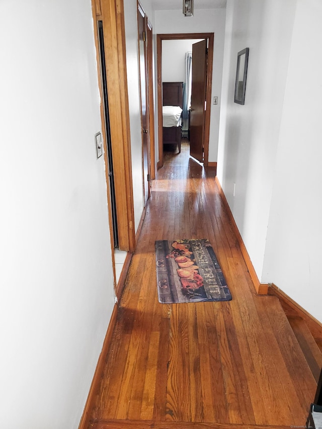 hallway featuring baseboards and hardwood / wood-style floors