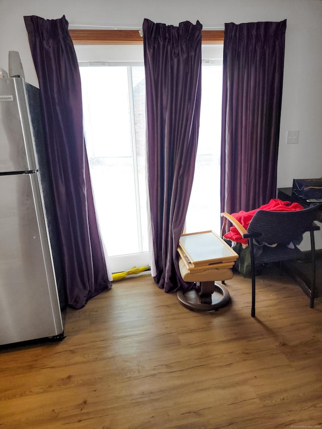 bedroom with multiple windows, wood finished floors, and freestanding refrigerator