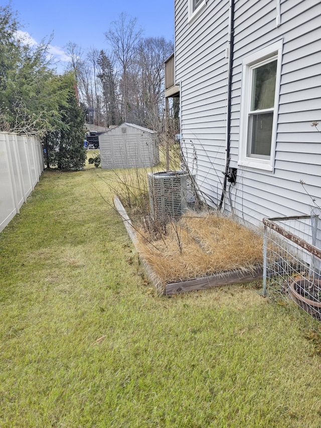 view of yard with an outbuilding, central AC, a shed, and fence