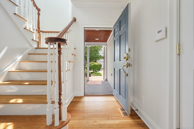 entrance foyer with visible vents, light wood-style flooring, ornamental molding, baseboards, and stairs