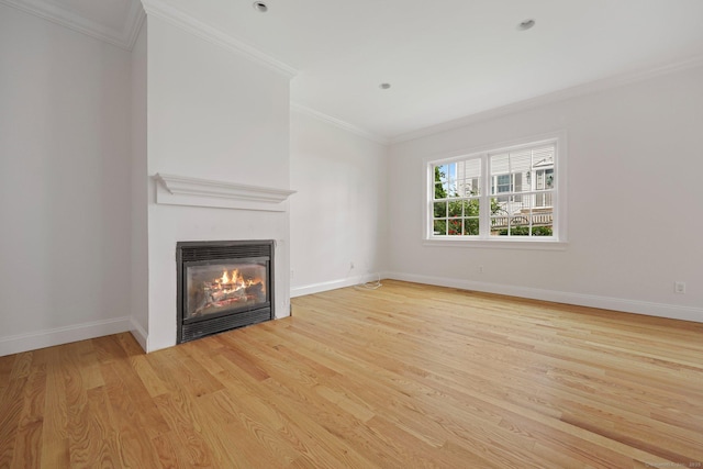 unfurnished living room with ornamental molding, light wood finished floors, a glass covered fireplace, and baseboards