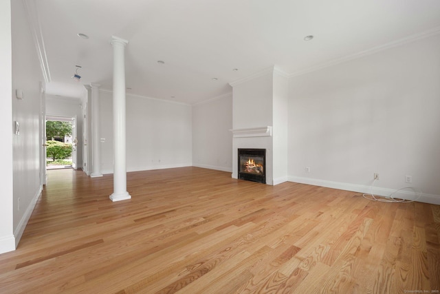 unfurnished living room featuring light wood-style floors, a glass covered fireplace, and decorative columns