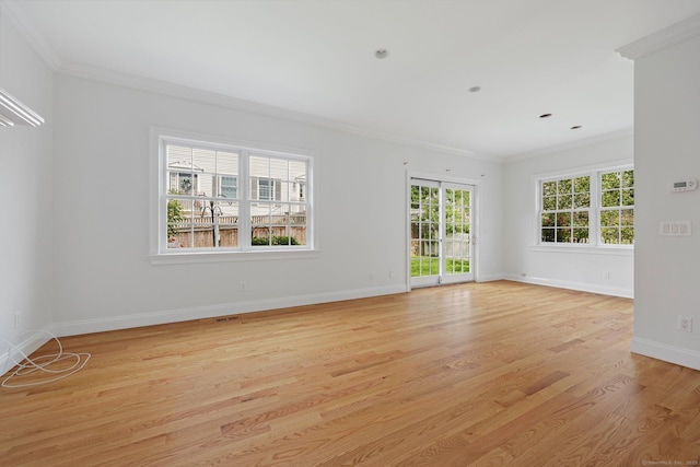 empty room featuring ornamental molding, light wood-type flooring, and baseboards