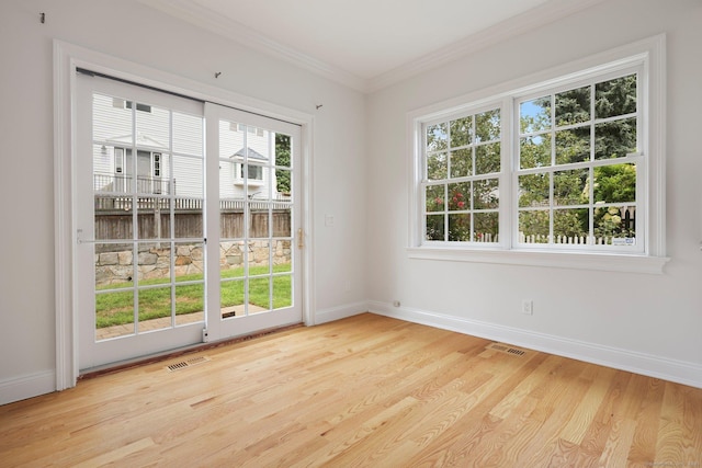 spare room featuring light wood-type flooring, baseboards, visible vents, and ornamental molding