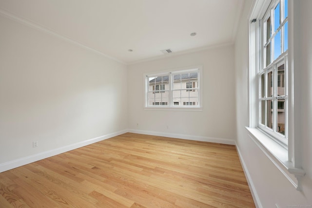 empty room featuring baseboards, visible vents, light wood-style flooring, and ornamental molding