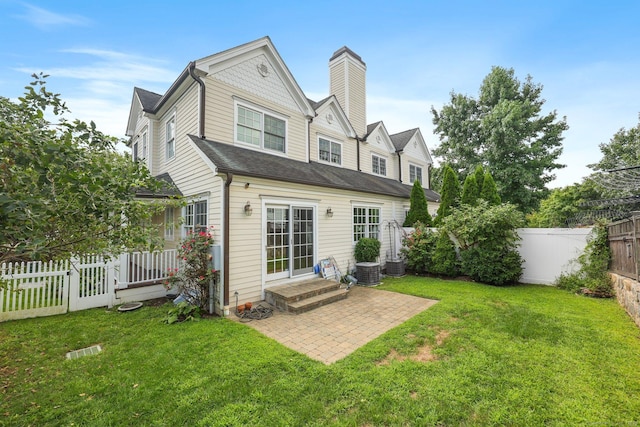 back of house featuring entry steps, a fenced backyard, a lawn, and a patio