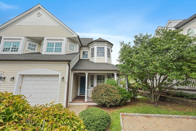 view of front of house with a garage, a shingled roof, and a porch