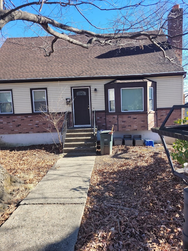 single story home featuring brick siding, a chimney, and roof with shingles