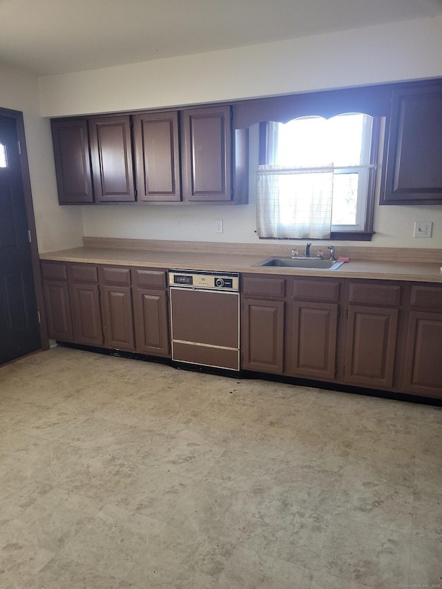 kitchen featuring light floors, light countertops, a sink, and dishwashing machine