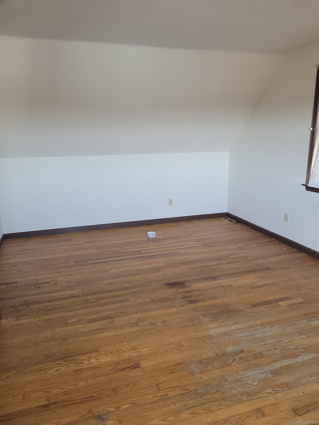 additional living space with vaulted ceiling, wood finished floors, and baseboards