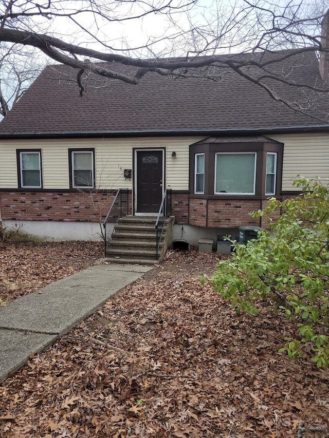 view of front facade with a shingled roof and brick siding