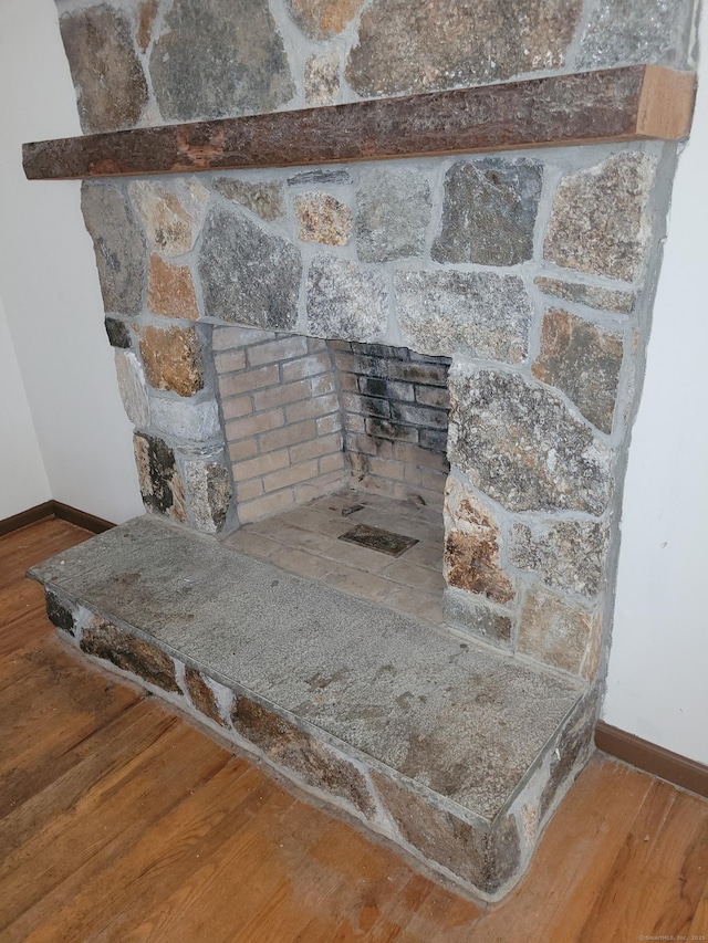 interior details featuring baseboards, wood finished floors, and a stone fireplace