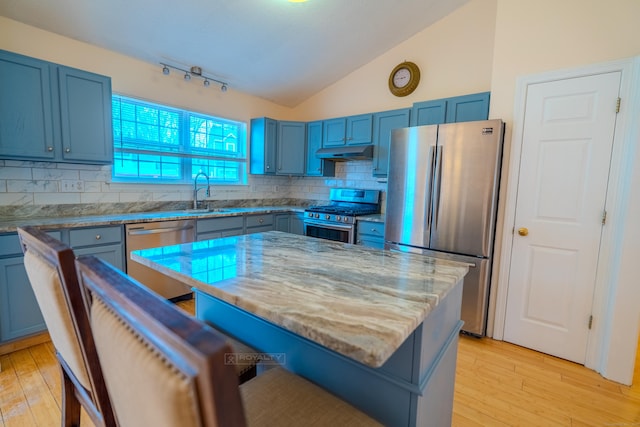 kitchen with under cabinet range hood, blue cabinetry, appliances with stainless steel finishes, and lofted ceiling