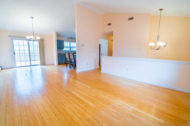 unfurnished living room featuring baseboards, visible vents, high vaulted ceiling, light wood-style flooring, and a notable chandelier