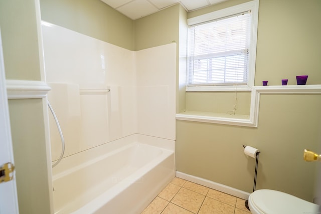 bathroom with baseboards, toilet,  shower combination, and tile patterned flooring