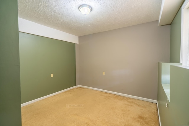 empty room with light carpet, a textured ceiling, and baseboards