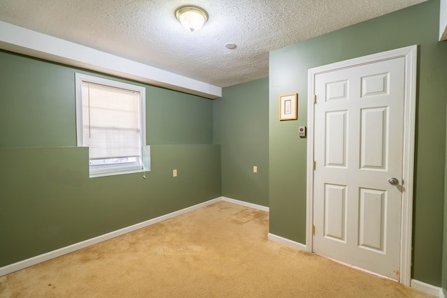 empty room with a textured ceiling, baseboards, and light carpet