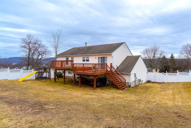 back of house with stairway, a lawn, a deck, a fenced backyard, and a gate