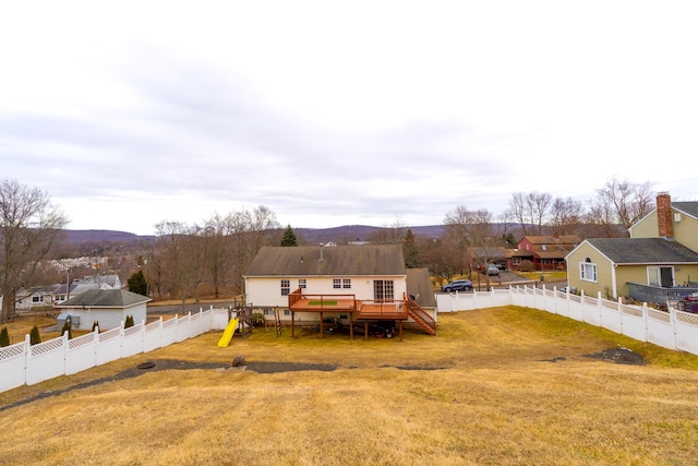 rear view of house with a playground, a yard, a fenced backyard, and a wooden deck