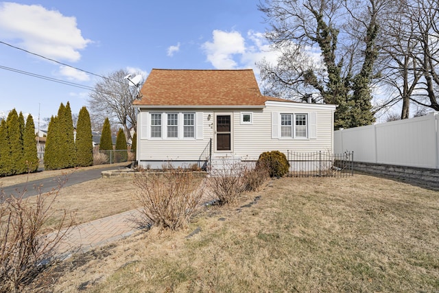 view of front of house featuring a front yard, roof with shingles, and fence