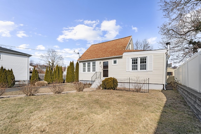 rear view of property with entry steps, roof with shingles, fence, and a yard