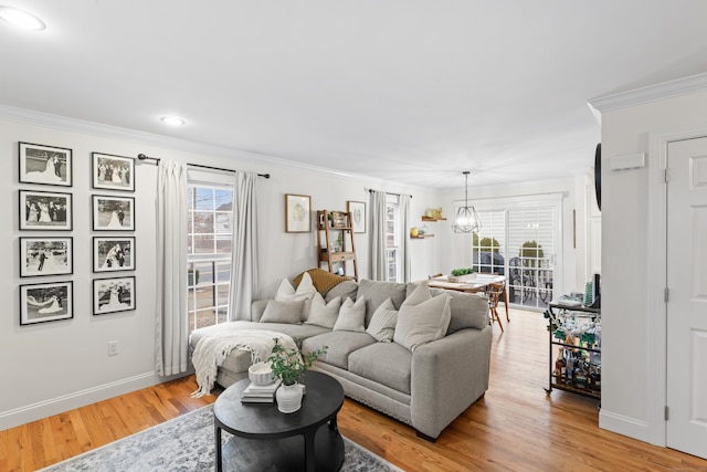 living area featuring baseboards, ornamental molding, and light wood-style floors