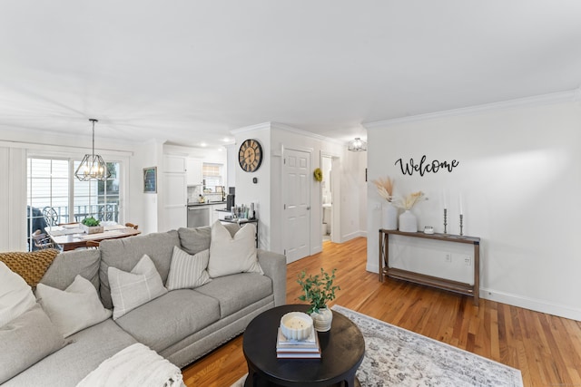 living area featuring a chandelier, crown molding, light wood-style flooring, and baseboards